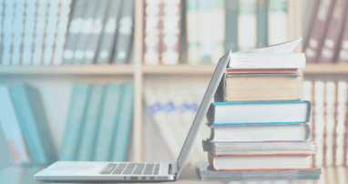 An open laptop against a stack of books